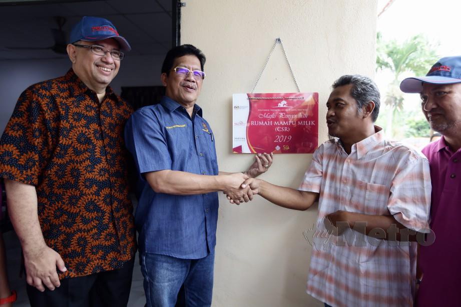  SYED Hussian (kiri) dan Mohd Fasiah (kanan) menyerahkan plak perasmian rumah kepada Mohd Khairul. FOTO Roslin Mat Tahir