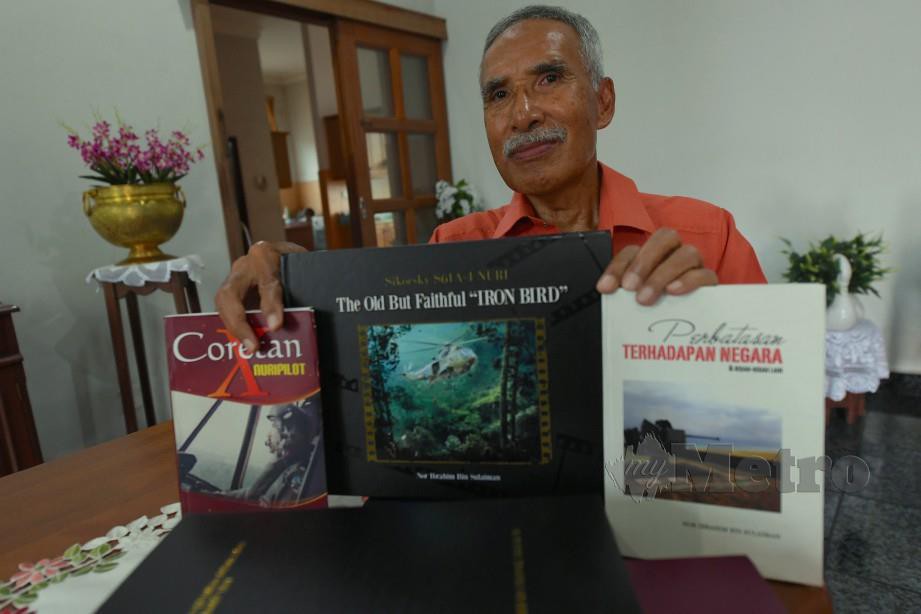Dr Nor Ibrahim menunjukkan buku mengenai perjuangan anggota TUDM menentang komunis yang ditulisnya. FOTO Bernama