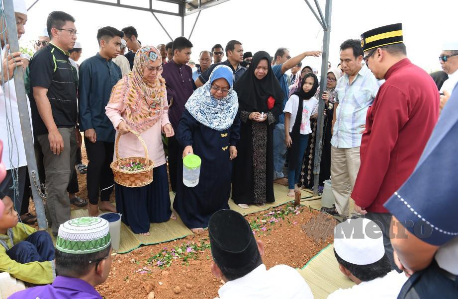 DR Mizan Adilah menyiram air mawar ke pusara arwah suaminya di Tanah Perkuburan Islam Kampung Ginching, Sepang hari ini. FOTO BERNAMA.