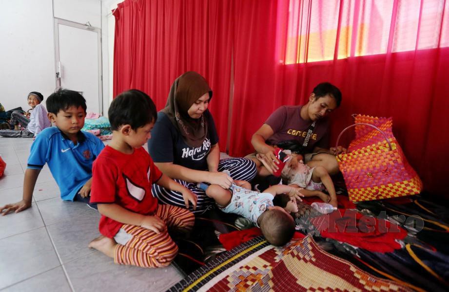 Mangsa banjir, Mohd Nor Azhar Mohd Zaki, 30, dan isteri Siti Mariam Omar, 26, bersama anak mereka tinggal di pusat pemindahan Dewan Haji Mohamad Padil selepas rumah mereka dinaiki air. FOTO Abdullah Yusof