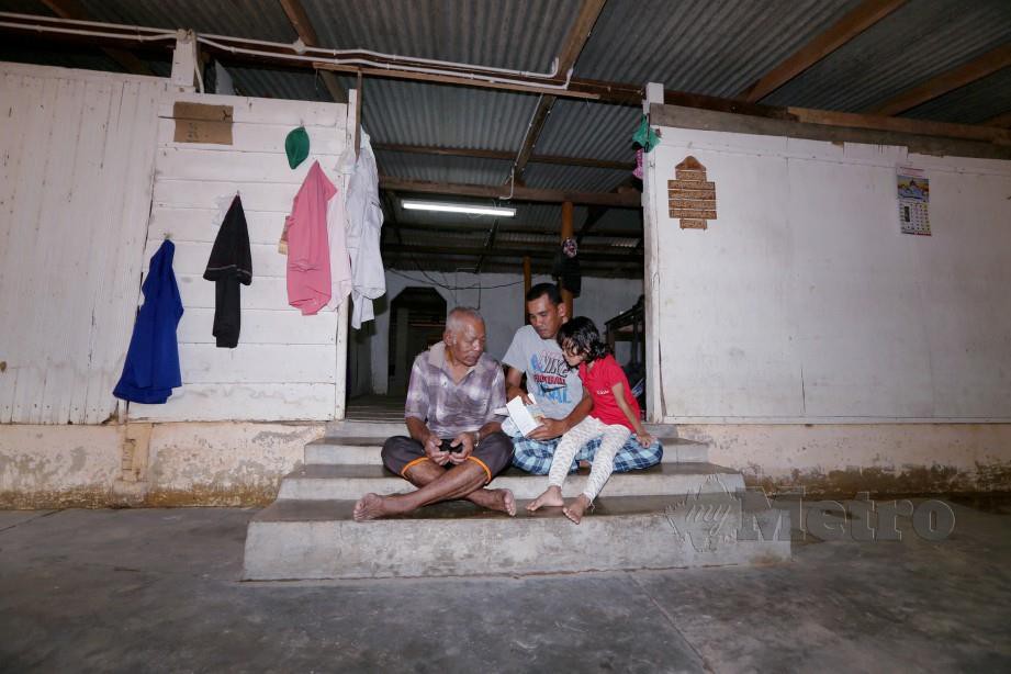 Mohamad Isnin bersama bapanya di rumah mereka yang kerap dilanda banjir. FOTO Imran Makhzan
