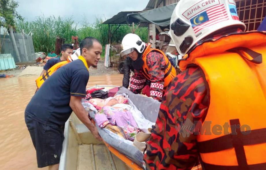 ANGGOTA bomba membantu memindahkan penduduk yang sakit selepas kediamannya di Kampung Paya Kenangan dilanda banjir. FOTO Ihsan JBPM.