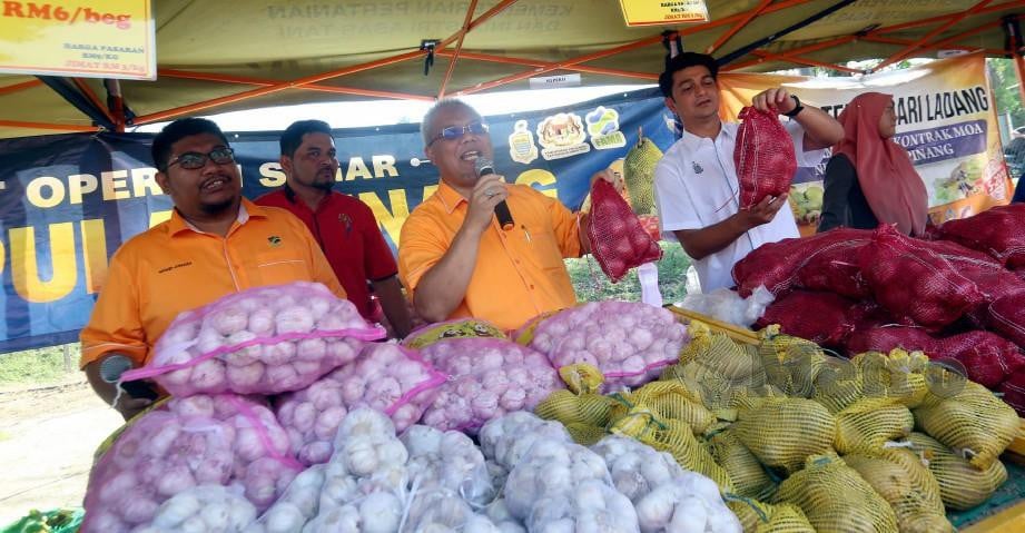 MUHAMMAD Faiz (dua dari kanan) bersama Ishak (tiga dari kiri) menjual bawang merah dan bawang putih pada harga murah sempena Bazar Peduli Rakyat di PPK Kampung Pelet. FOTO Danial Saad.