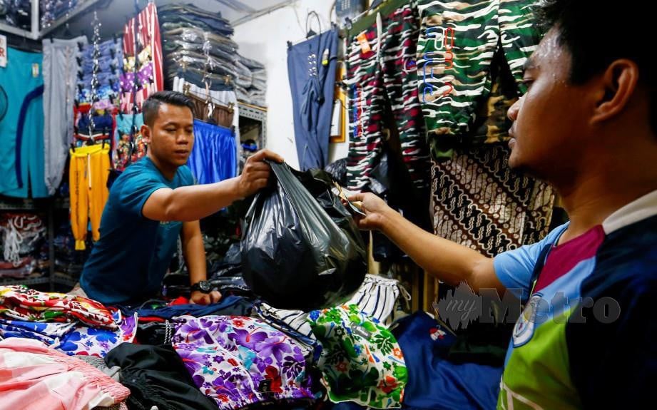 PENIAGA menggunakan plastik untuk membungkus pembelian di Jakarta. FOTO REUTERS
