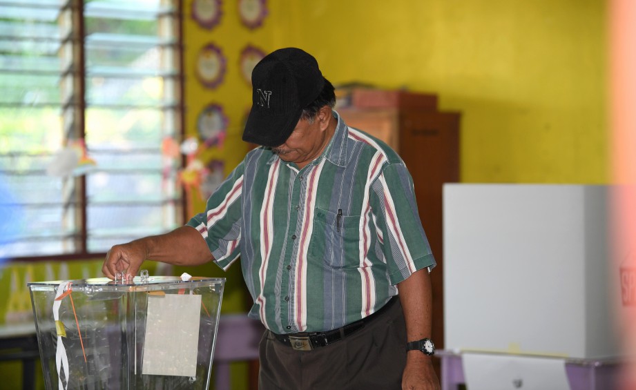 PENGUNDI pertama Juanis Puduk, 72, memasukkan kertas undi ke dalam peti undi di pusat mengundi, Sekolah Kebangsaan Our Lady of Fatima (M) Kelatuan, hari ini. FOTO BERNAMA.