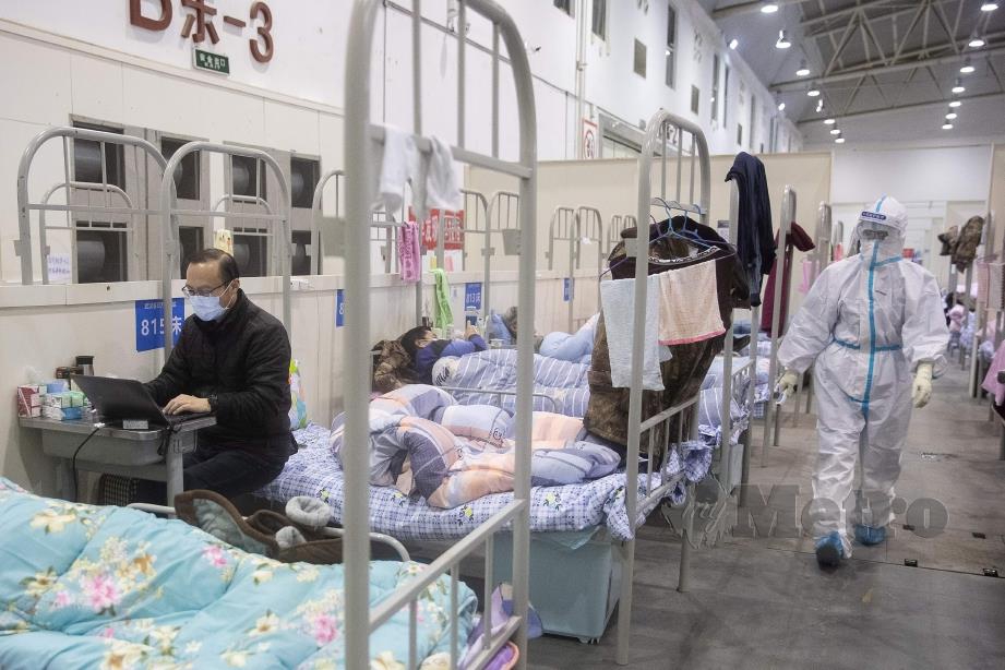 LELAKI (kiri) mempunyai gejala ringan Covid-19 menggunakan laptop di pusat pameran yang dijadikan hospital di Wuhan. FOTO AFP