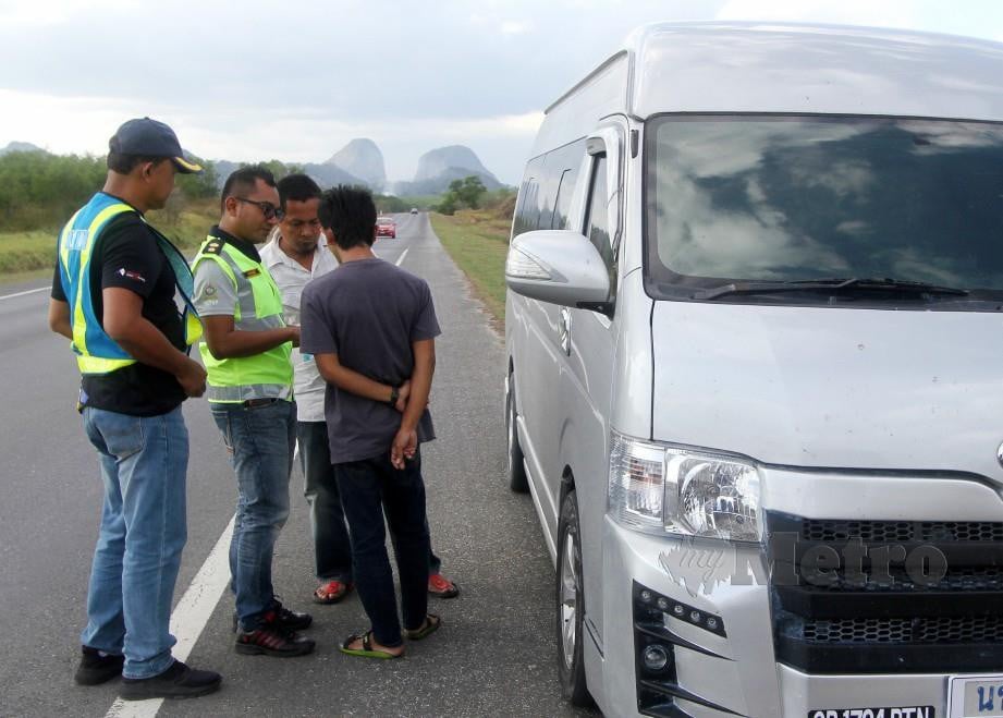 TIMBALAN Pengarah Jabatan Pengangkutan Jalan (JPJ) Perlis Mahazir Abd Majid (dua kiri) memeriksa dokumen pemandu van dari Thailand yang dipercayai dijadikan teksi haram. FOTO Bernama