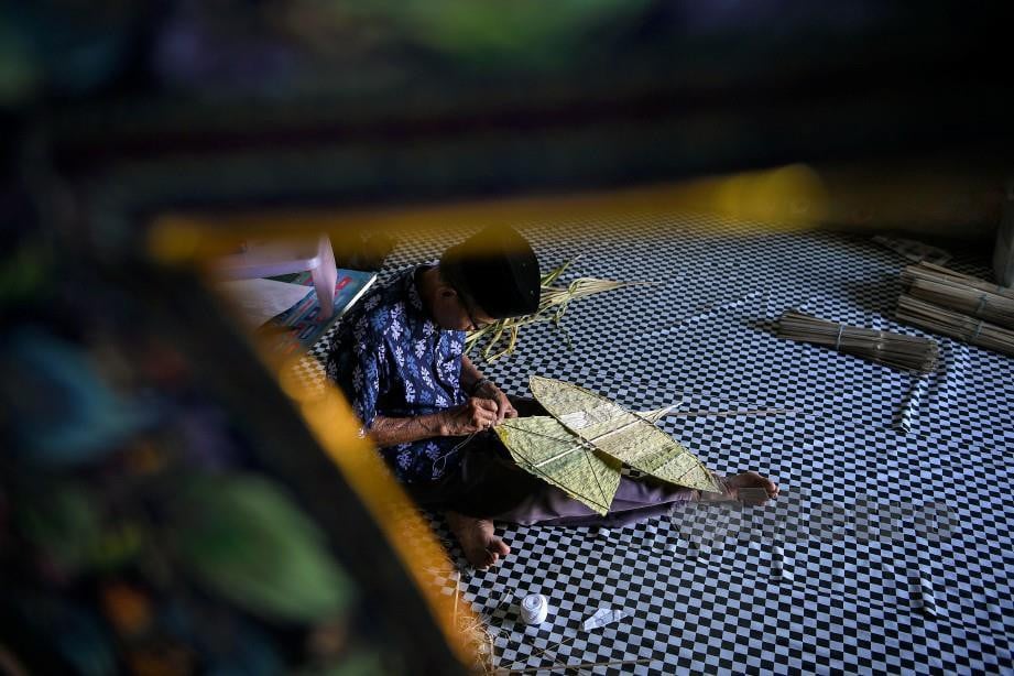 PAK Non melekat dan menjahit daun palas pada rangka badan Wau Helang. FOTO Bernama
