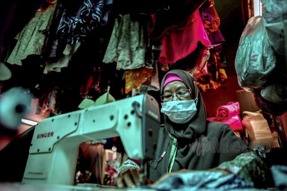 ROFIAH Mat Ali, 60, menjahit baju tempahan pelangganya di Pasar Besar Kuantan. Menurutnya, walaupun pada Aidilfitri, tempahan baju raya yang diterimanya pada tahun ini sangat berkurangan berikutan pandemik Covid-19. FOTO Farizul Hafiz Awang