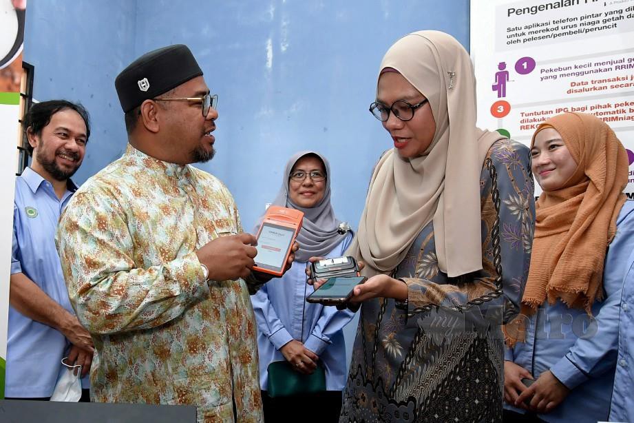 MOHD Khairuddin (dua, kiri) melihat penggunaan peralatan bagi aplikasi RRIMniaga bagi pendaftaran insentif pengeluaran getah yang disediakan kepada pelesen, pembeli dan peruncit. FOTO Bernama