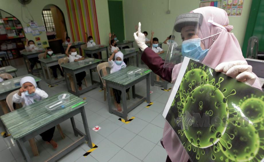 Guru, Nor Azliza Che Soh menunjukkan bahayanya virus Covid-19 ketika sesi pembelajaran pada tinjauan pembukaan semula prasekolah di Jelutong. FOTO DANIAL SAAD