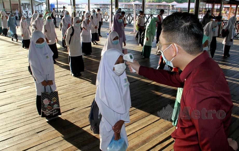 GURU SK Pulau Gaya, Sabah memeriksa suhu murid pada hari pertama pembukaan semula sesi persekolahan. FOTO Malai Rosmah Tuah