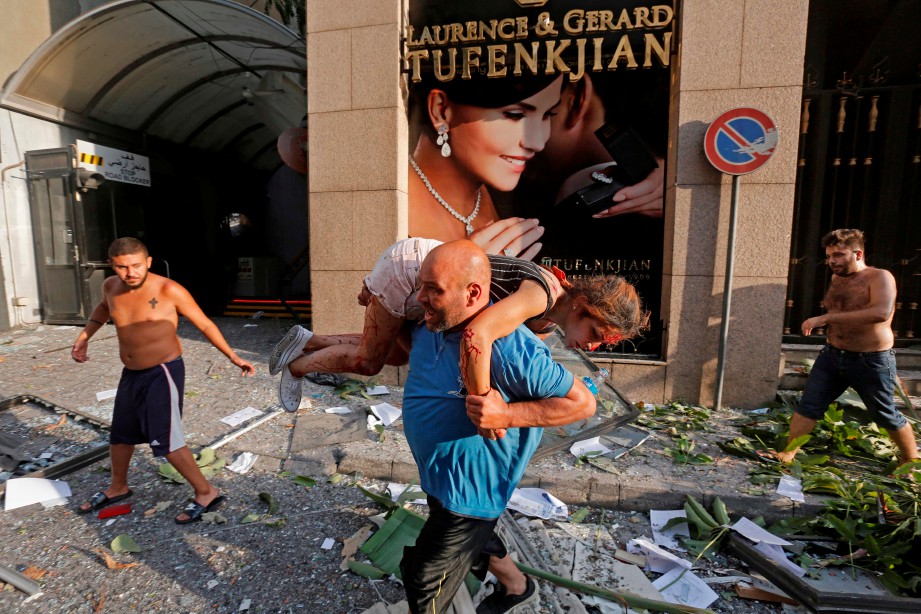 SEORANG lelaki membantu gadis yang cedera di kawasan yang musnah akibat letupan di pelabuham Beirut. FOTO AFP