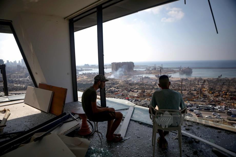 DUA lelaki melihat kemusnahan pelabuhan Beirut dari bangunan yang turut megalami kerosakan akibat letupan pelabuhan itu. FOTO AFP