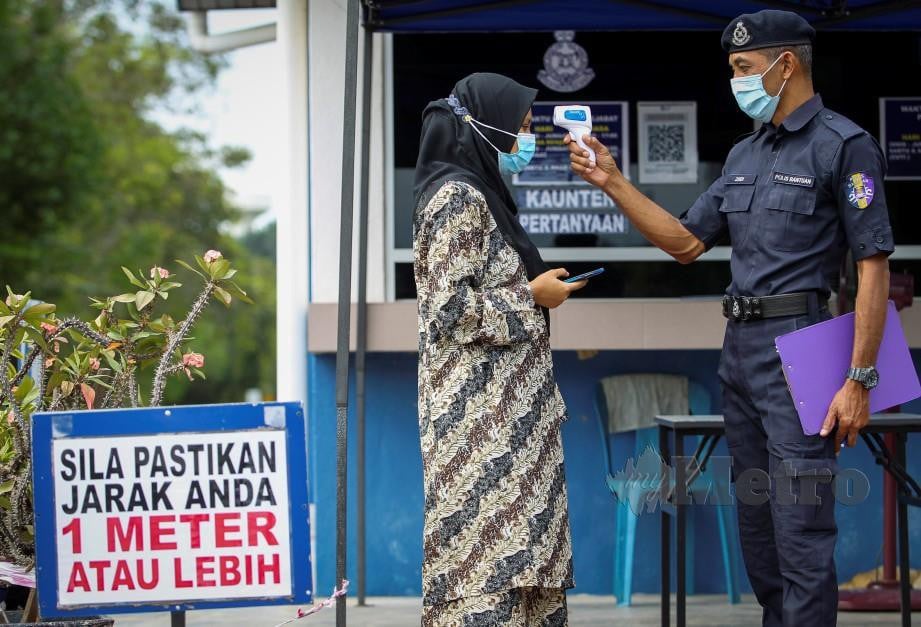 POLIS Bantuan UiTM memeriksa suhu penuntut yang masuk ke kampus di Lendu.  FOTO Azrul Edham Mohd Aminuddin