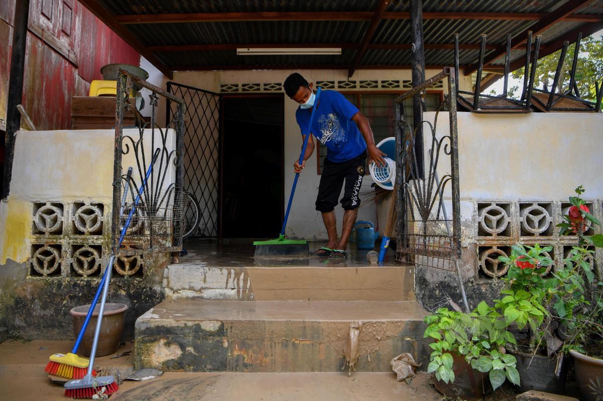 SUKARELAWAN setempat bergotong royong membersihkan rumah penduduk warga emas yang terjejas susulan banjir di Kampung Gadek Dalam, semalam. FOTO BERNAMA