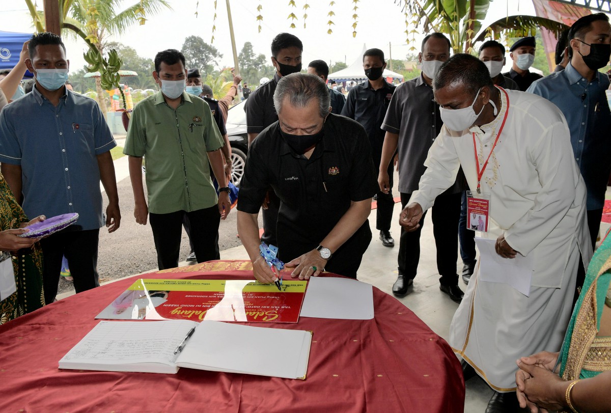 MUHYIDDIN menandatangani plak ketika menghadiri Sambutan Hari Deepavali 2020 DUN Gambir. Turut hadir Pengerusi Kuil Sri Maha Mathurai Veeran Sri Maha Kaaliyamman Sagil R.Philip (kanan). FOTO Bernama