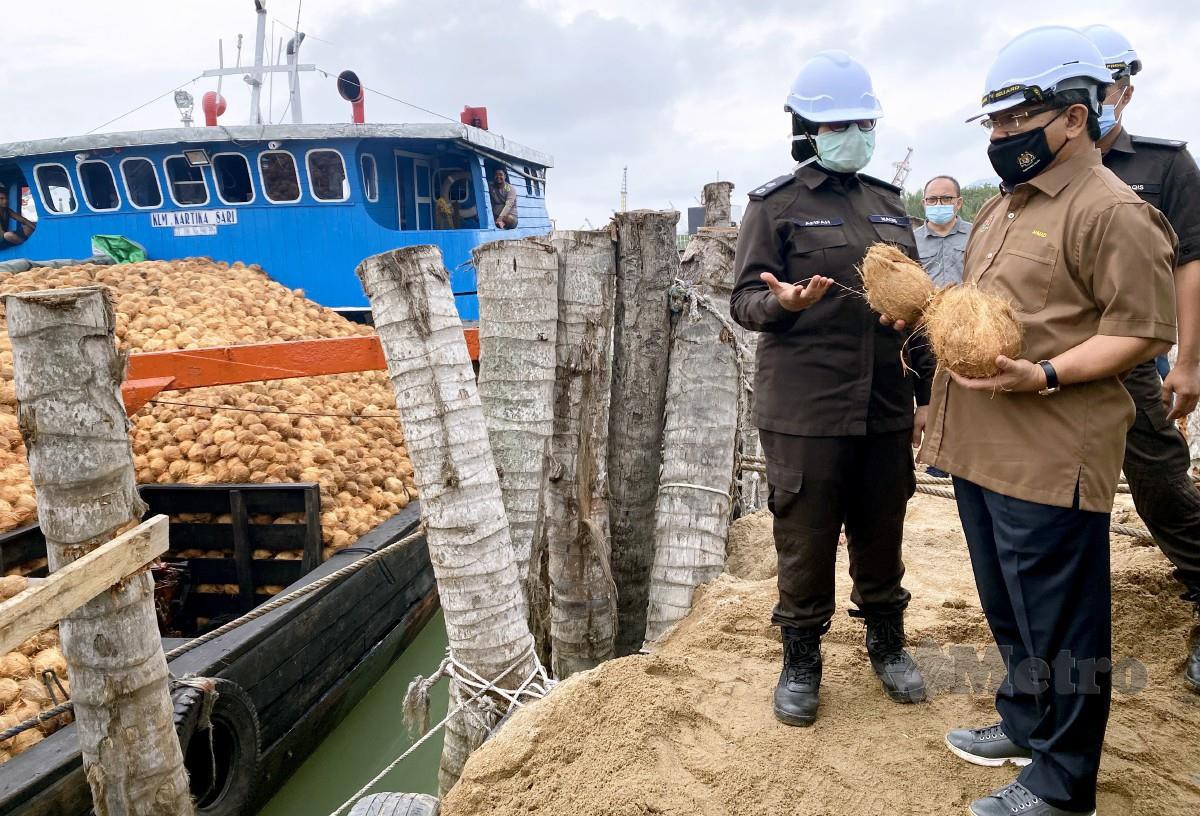 AHMAD Hamzah (kanan) mendengar penerangan berhubung kelapa yang dibawa masuk ke negara ini melalui Jeti Right Base, di Pelabuhan Batu Pahat. FOTO Bernama