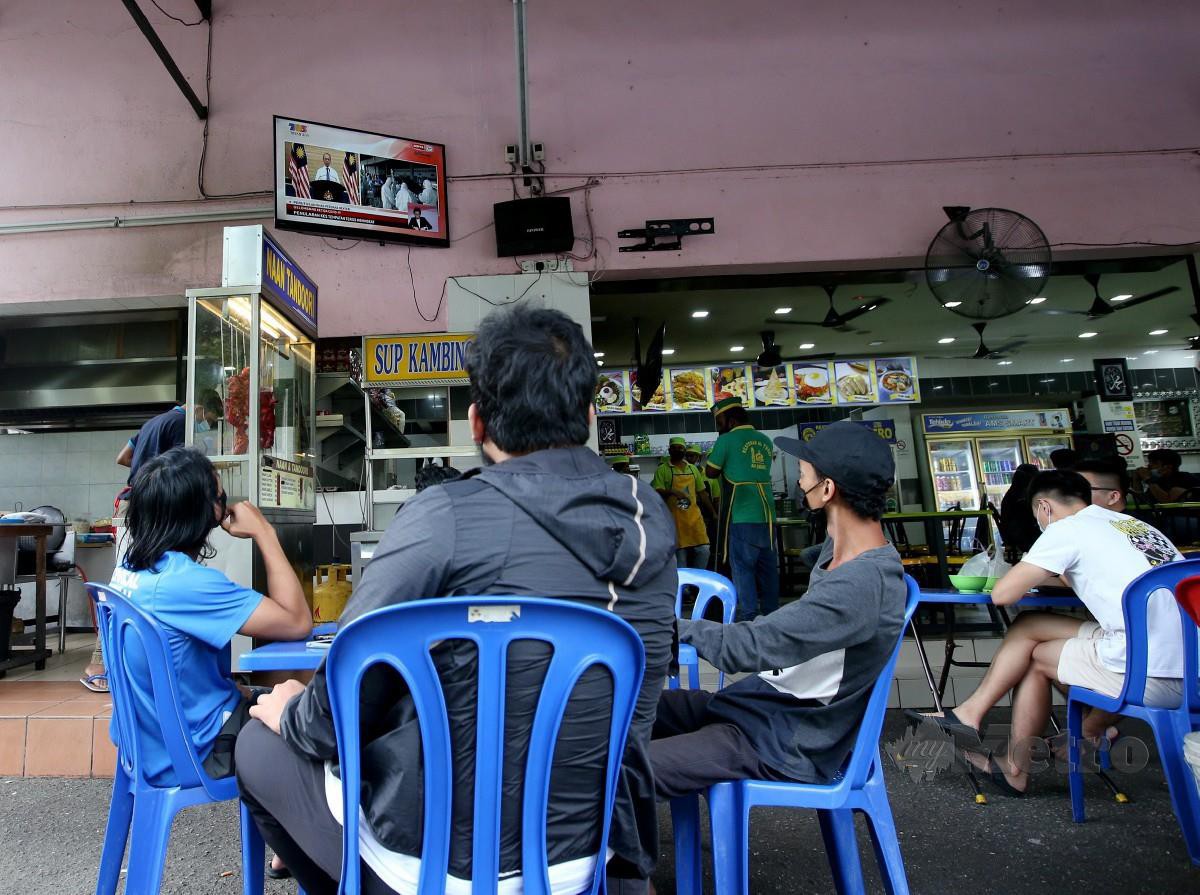 PELANGGAN restoran di Kuala Lumpur menonton Perutusan Khas Perdana Menteri berhubung pelaksanaan Perintah Kawalan Pergerakan (PKP). FOTO Eizairi Shamsudin