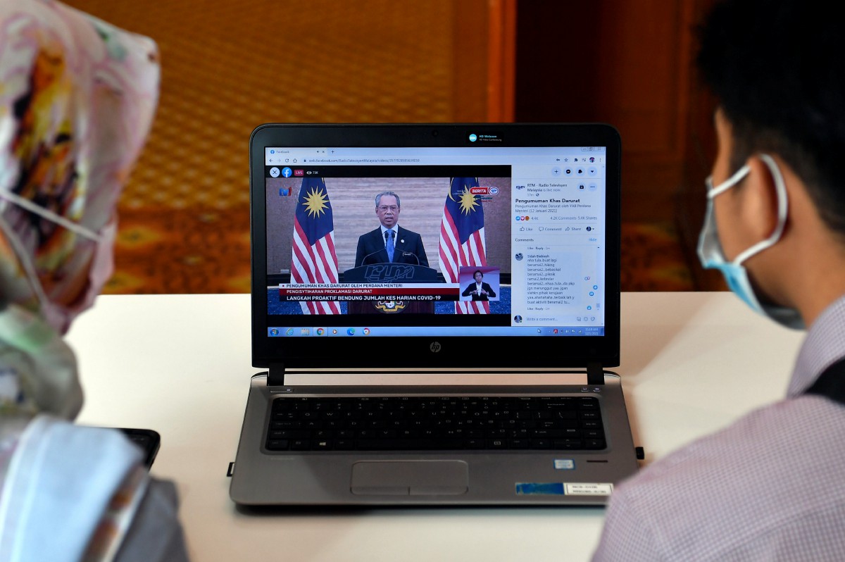 ORANG awam mendengar Pengumuman Khas Darurat oleh Perdana Menteri melalui peranti digital. FOTO Bernama