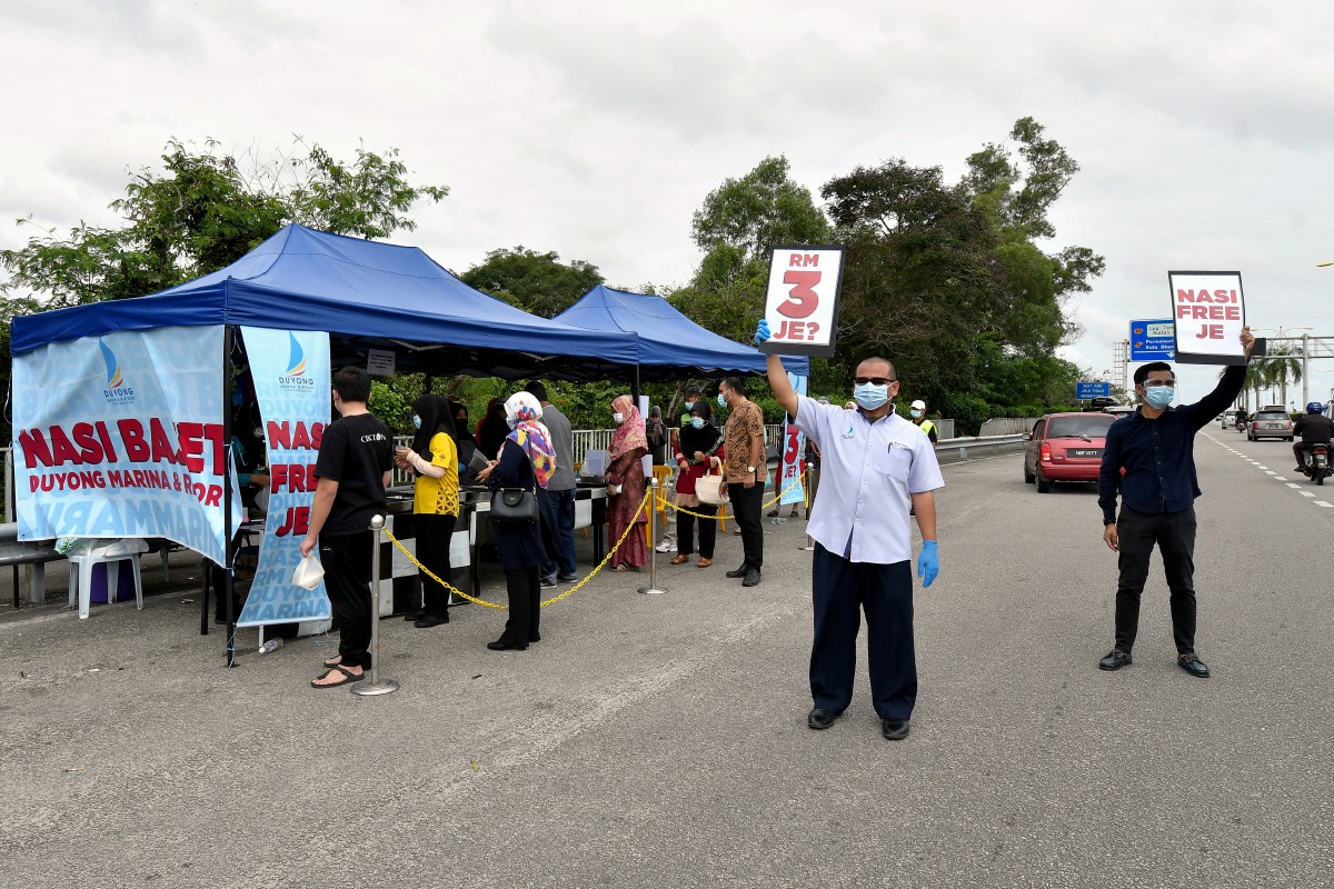 WAN Mohd Faizul (dua, kanan) bersama kakitangannya Azim Mokhtar memegang poster nasi bajet bagi menarik perhatian orang ramai. FOTO Bernama