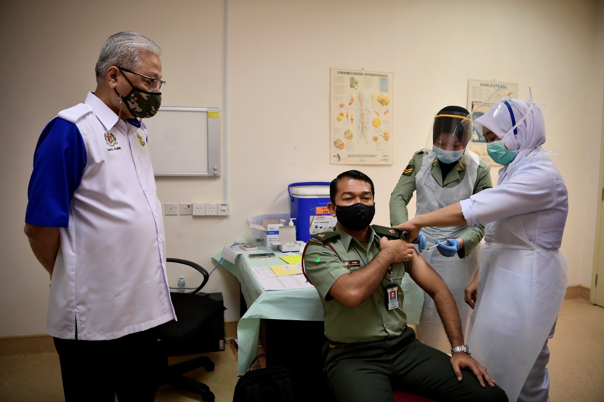 ISMAIL Sabri (kiri) menyaksikan anggota Tentera Darat, Mejar Mohd Fuad Nazri menerima suntikan vaksin. FOTO Bernama