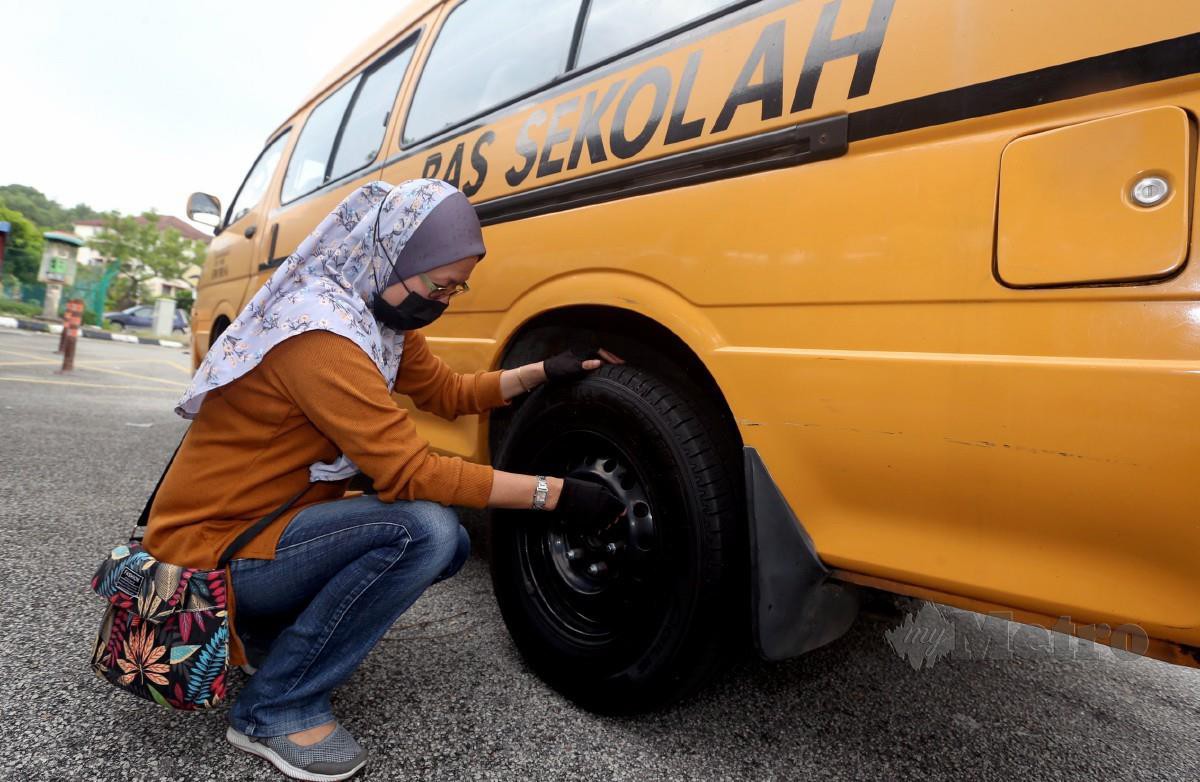 Pengusaha bas sekolah, Saadiah Ismail, 41, memeriksa tayar bas sekolah di Subang Perdana bagi persiapan menjelang pembukaan semula sesi persekolahan secara berperingkat. FOTO HAIRUL ANUAR RAHIM