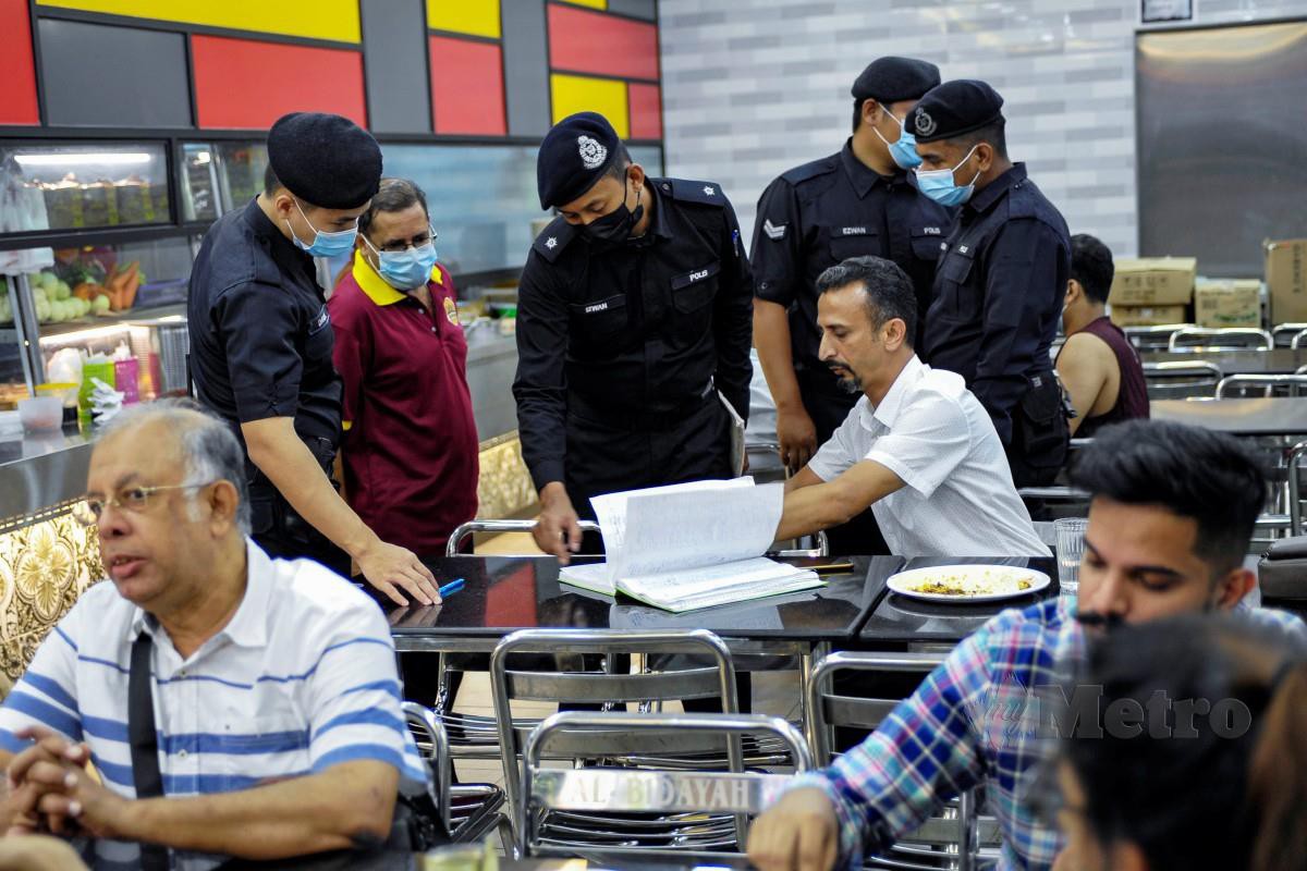 PEGAWAI polis memeriksa pematuhan prosedur operasi standard (SOP) di sebuah restoran di Jalan Masjid India, Kuala Lumpur. FOTO Aizuddin Saad.