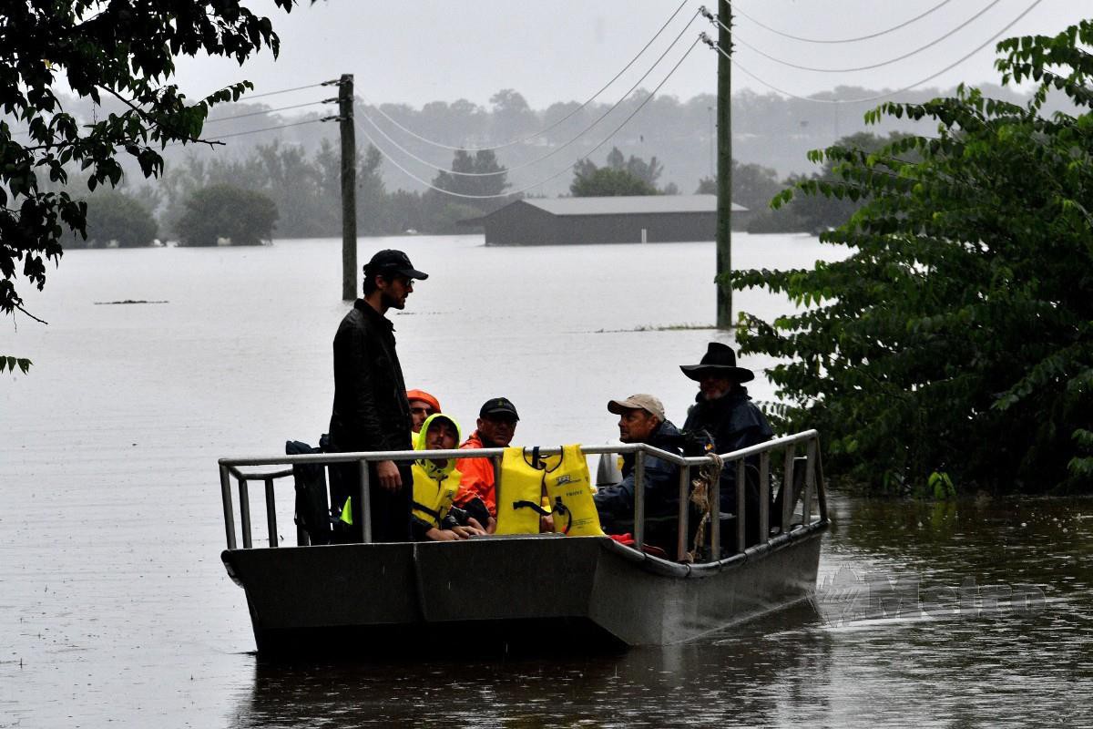 PENDUDUK menaiki bot di kawasan yang dilanda banjir. FOTO AFP