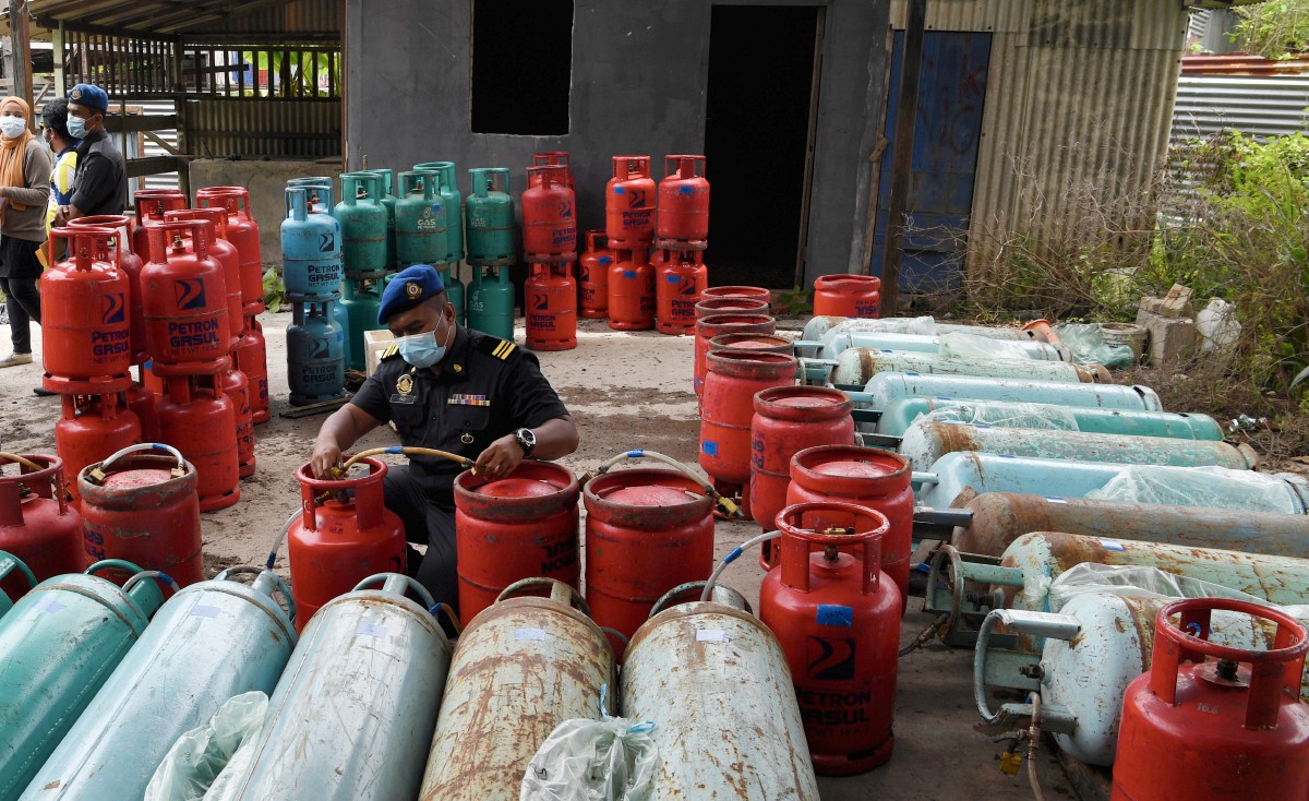 PEGAWAI penguat kuasa KPDNHEP, Muhamad Khairul Faizi Yahaya memeriksa sebahagian LPG DAN minyak masak bersubsidi bernilai hampir RM50,000 yang dirampas. FOTO Bernama.