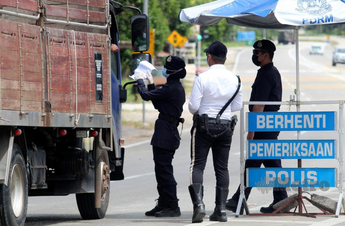 ANGGOTA polis memeriksa dokumen perjalanan pemandu  pada pelaksanaan Perintah Kawalan Pergerakan (PKP) di sekatan jalan raya (SJR) di Bukit Yong, Kelantan. FOTO Nik Abdullah Nik Omar.