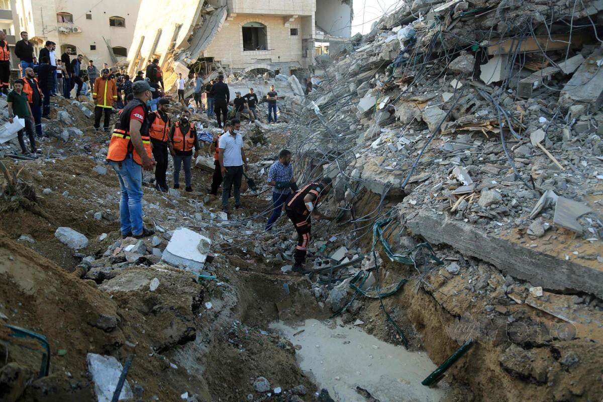 PARAMEDIK Palestin mencari mangsa di rumah milik keluarga al-Tanani yang runtuh akibat serangan udara Israel. FOTO AFP