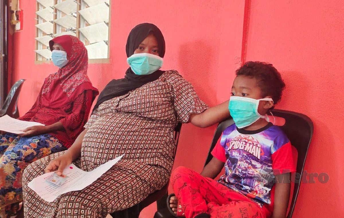 CHE Mas (tengah) bersama anak menunggu giliran untuk menerima vaksinasi. FOTO Syaherah Mustafa
