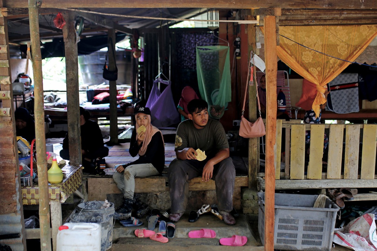 Nor Syazwani (kiri) menikmati makanan ringan ketika berehat seketika selepas bekerja di ladang kelapa sawit. FOTO BERNAMA