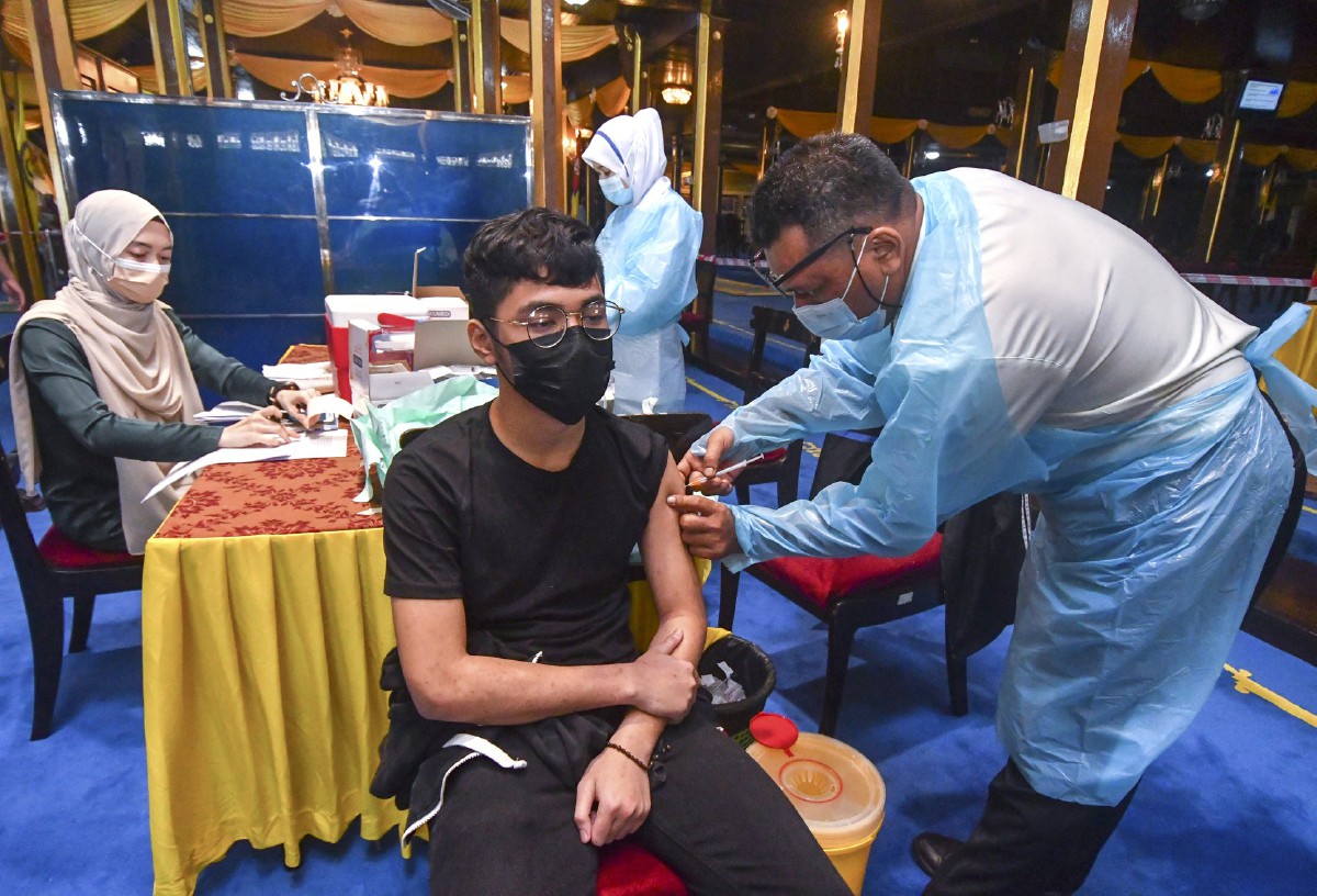 PETUGAS kesihatan memberikan suntikan vaksin kepada penerima di Istana Balai Besar. FOTO Bernama