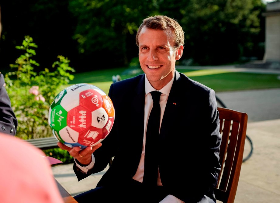 MACRON memegam bola sepak yang dihadiahkan Perdana Menteri Norway ketika mesyuarat di Elysee Palace, Paris pada 6 Julai 2018. FOTO AFP
