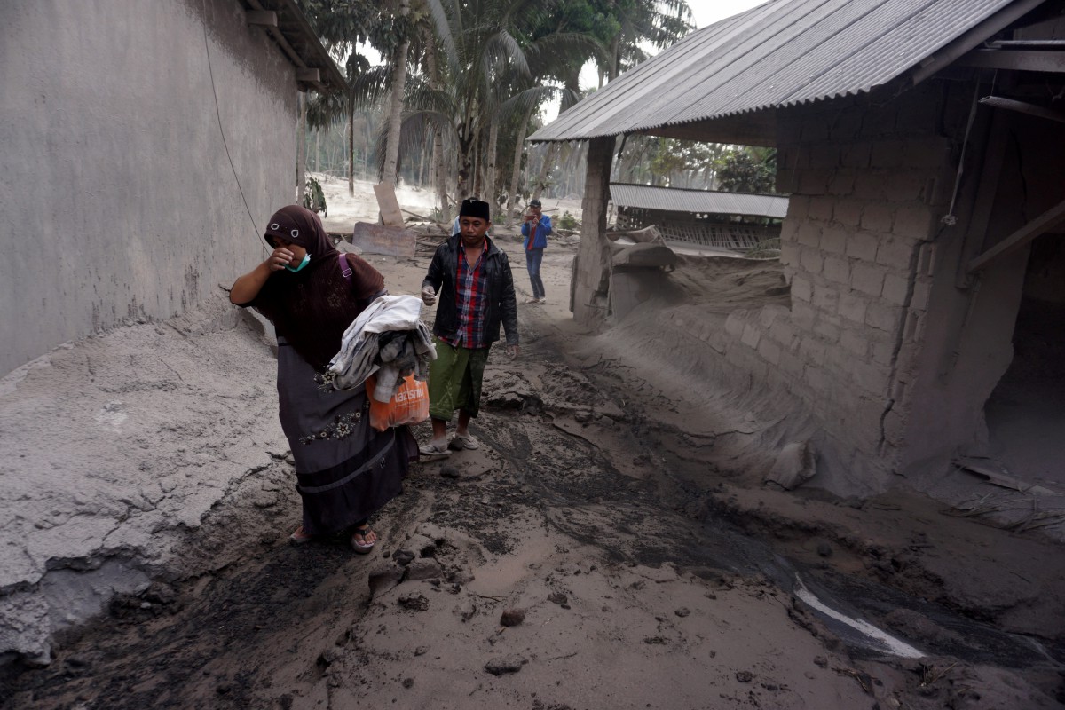 Penduduk Kampung Sumber Wuluh, Lumajang membawa barangan yang dapat diselamatkan selepas letusan Gunung Semeru. FOTO EPA