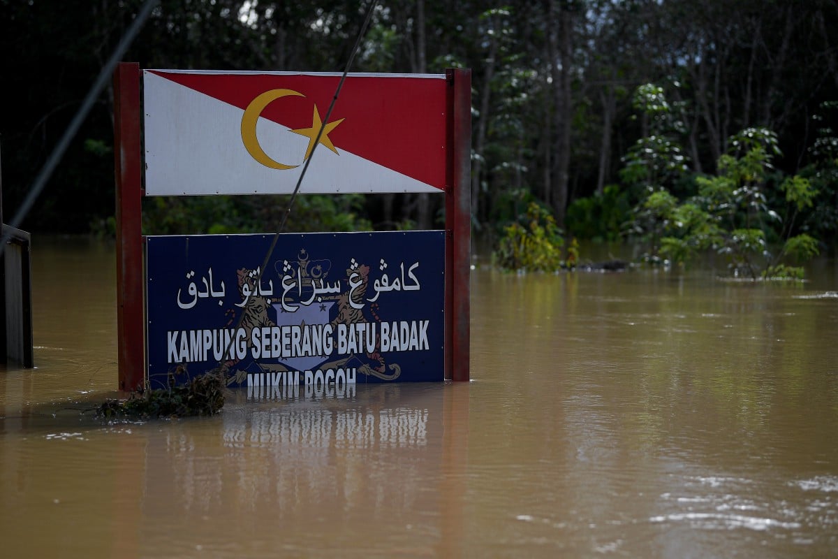 PAPAN tanda Kampung Seberang Batu Badak yang hampir ditenggelami air akibat banjir ketika tinjauan, semalam.  FOTO Bernama