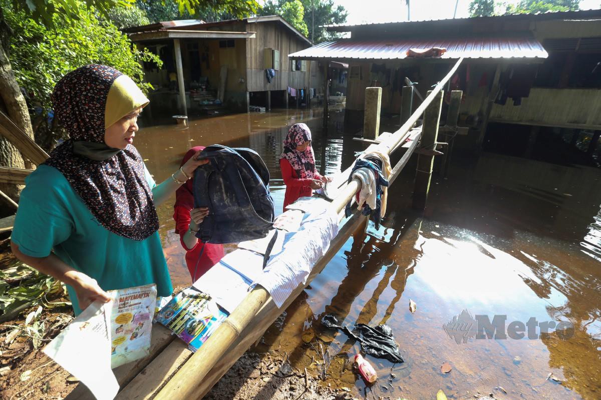 WAN Rohani (kiri)  bersama dengan anaknya memeriksa peralatan sekolah yang rosak akibat ditenggelami banjir. FOTO Nik Abdullah Nik Omar