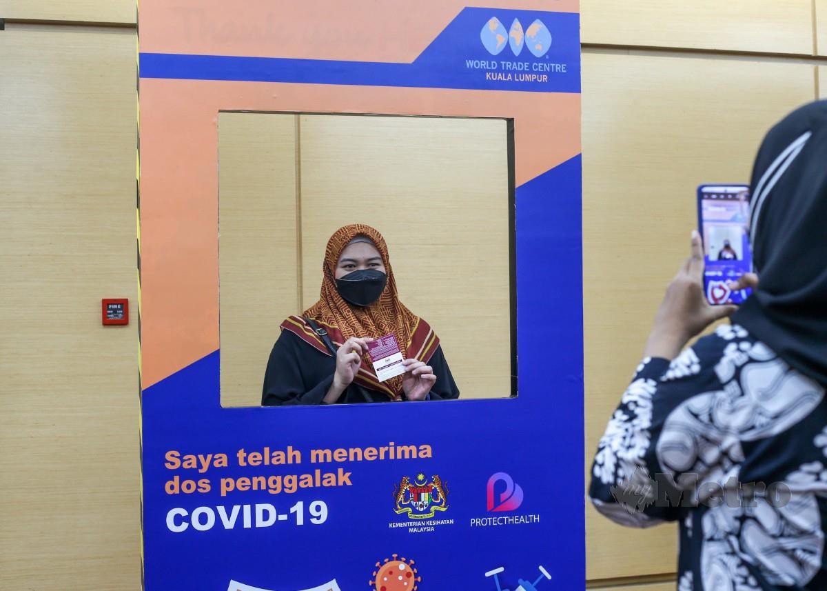 ORANG ramai bergambar di Pusat Pemberian Vaksin (PPV) Integrasi Pusat Dagangan Dunia Kuala Lumpur selepas menerima dos penggalak Covid-19, semalam. FOTO Aswadi Alias