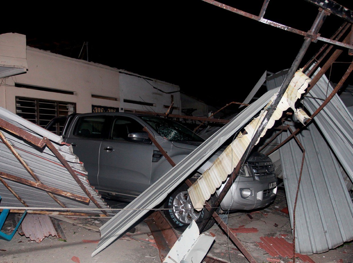 KENDERAAN dihempap bumbung rumah yang runtuh akibat dipukul ribut di Kampung Tawas, semalam. FOTO Bernama