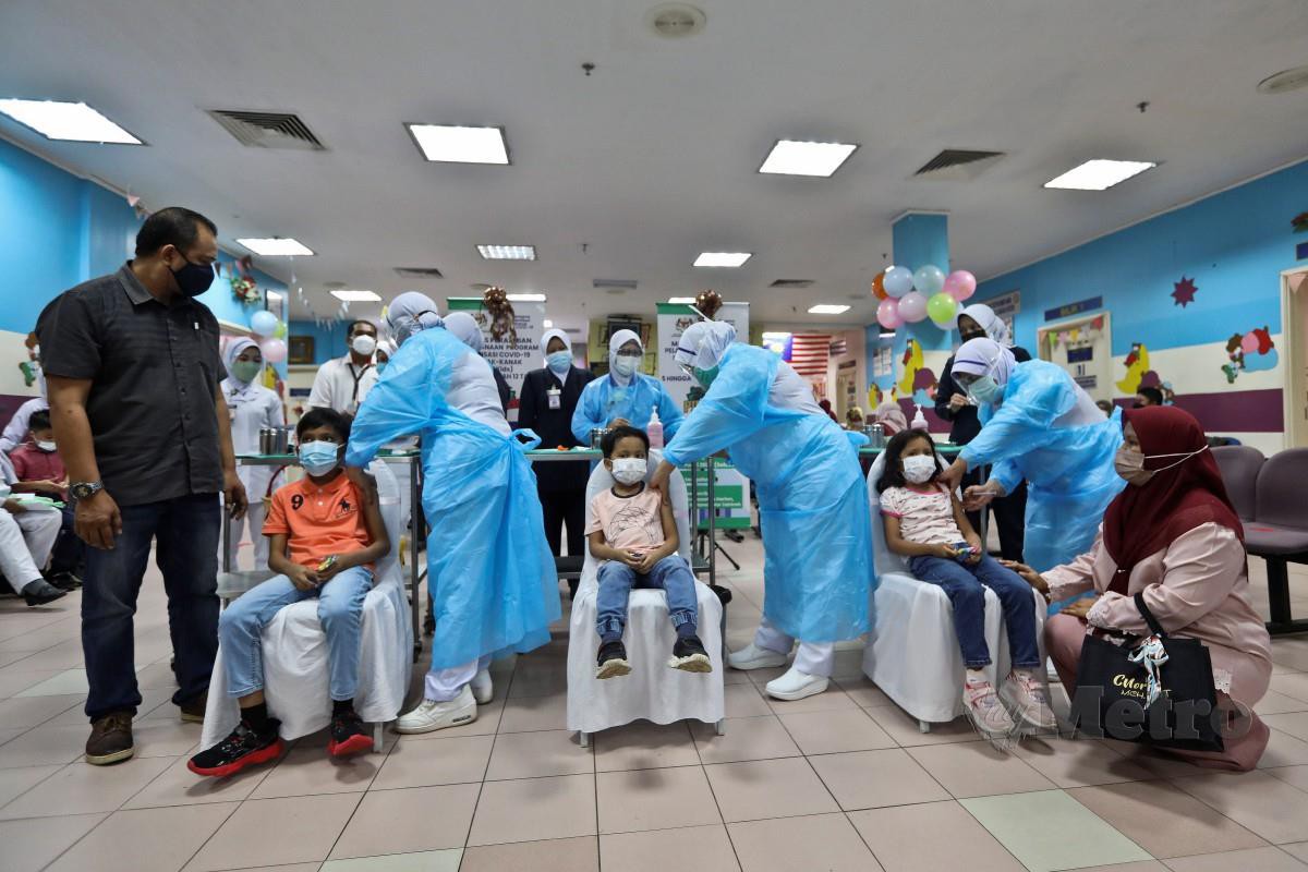 TIGA beradik, Nazriel Ariqin  Kamarul Azhar, 5 (tengah),   Nazeef Audric, 9 (dua kiri) dan Nurlisa Maureen, 6 ketika menjalani suntikan Vaksin pada Program Imunisasi Covid-19 Kanak-Kanak (PICKids) Peringkat Negeri di Hospital Sultanah Nur Zahirah (HSNZ).  FOTO Ghazali Kori