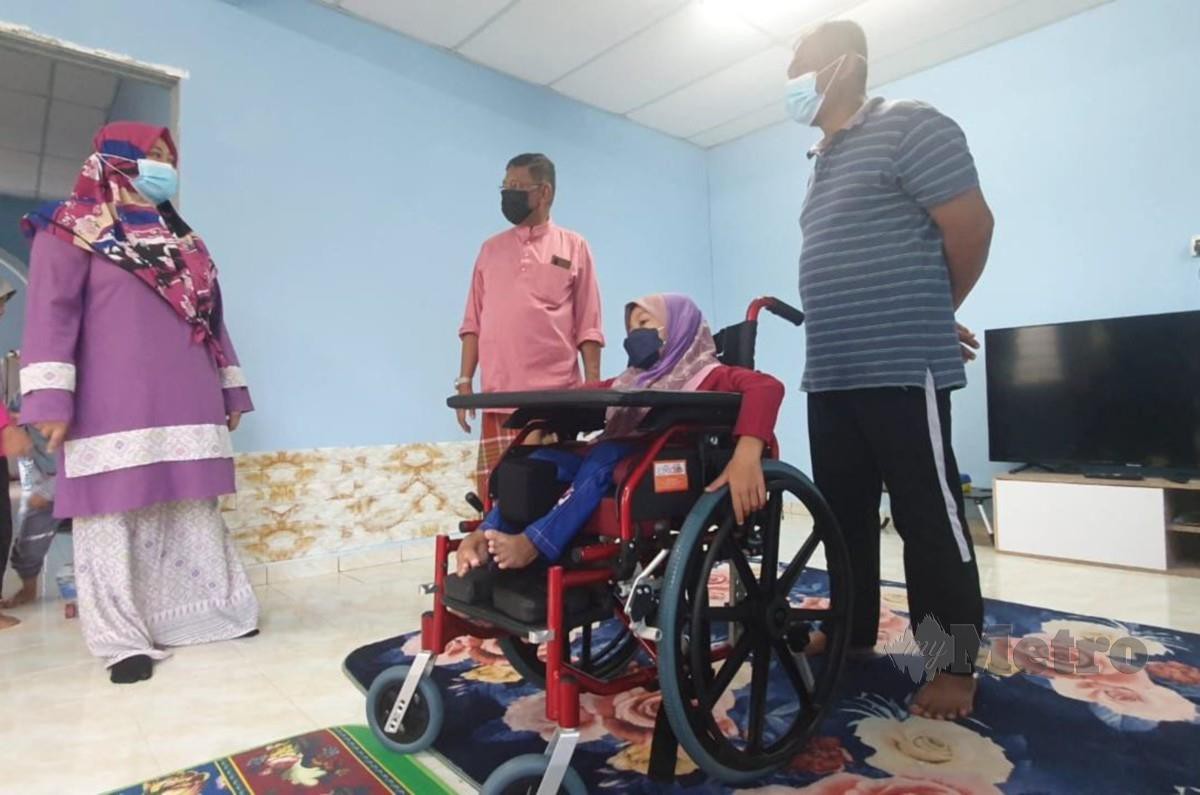 HANAFIAH (tengah) menyampaikan kerusi roda kepada  Nur Jannah Nazirah. FOTO Rosli Ilham
