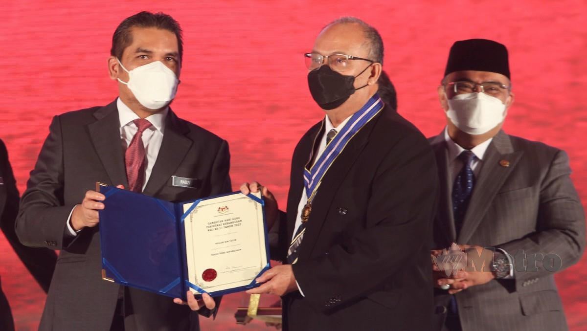 RADZI (kiri) menyampaikan Anugerah Tokoh Guru Kebangsaan Tahun 2022 kepada Roslan. FOTO Nik Abdullah Nik Omar