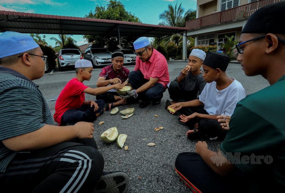 ZULKIFLI (tengah) menjamu durian kepada pelajar Madrasah Tahfiz Khoirul Uloom. FOTO Azrul Edham