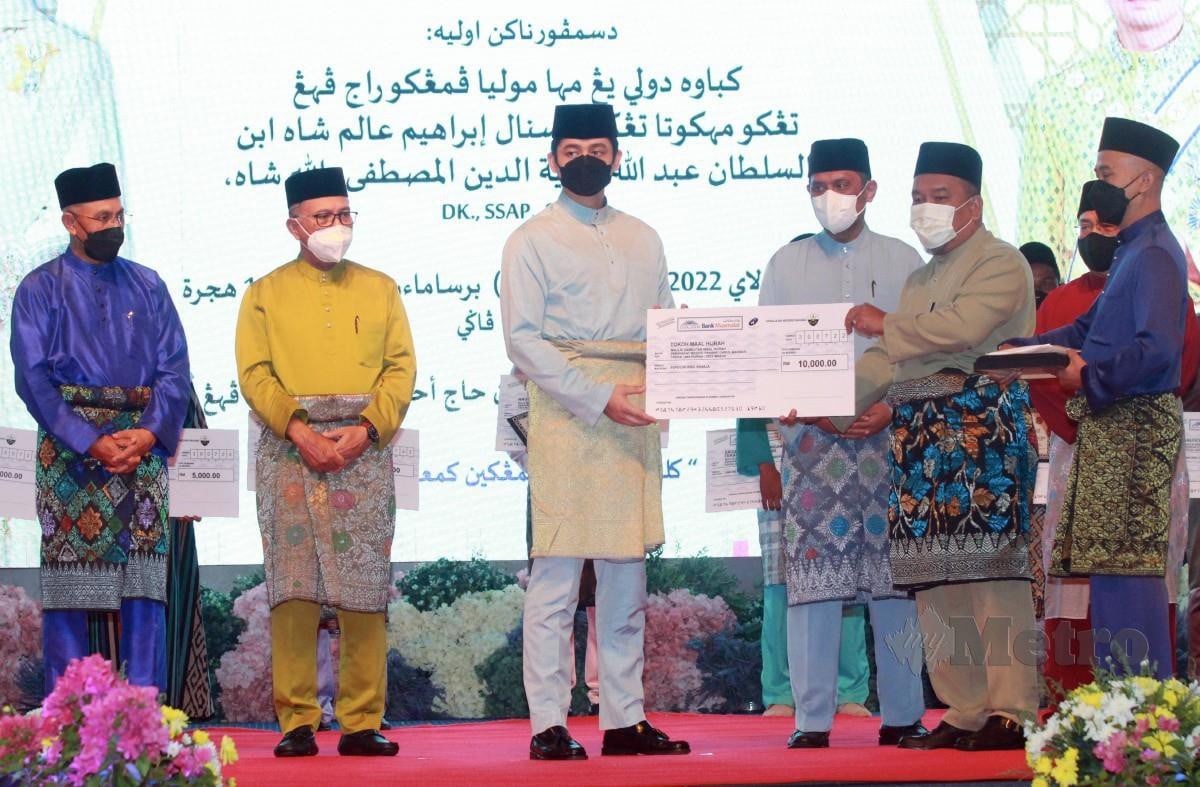 TENGKU Hassanal (tengah) menyerahkan sijil serta replika cek kepada Mohd Alhamadi pada Majlis Sambutan Maal Hijrah Peringkat Negeri Pahang. Turut kelihatan, Wan Rosdy Wan Ismail (dua kiri). FOTO Farizul Hafiz Awang