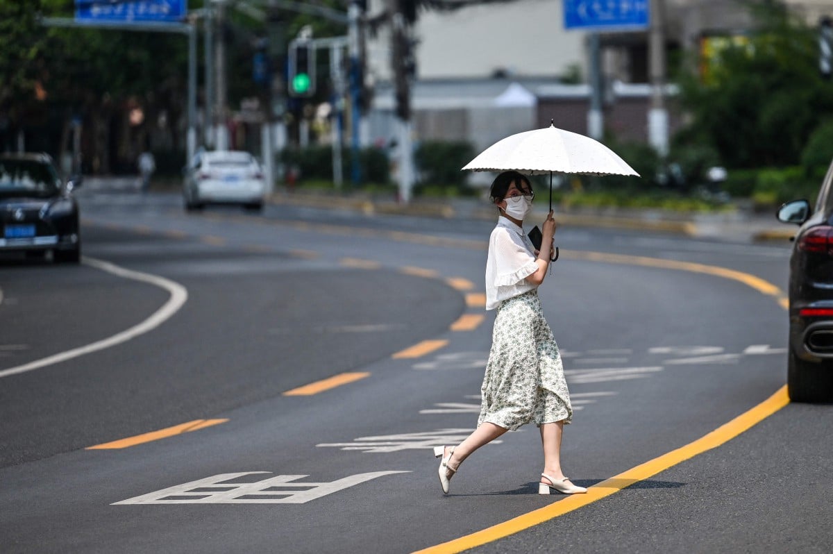 WANITA menggunakan payung bagi melindungi diri daripada cahaya matahari ketika cuaca panas di Shanghai, kelmarin. FOTO AFP