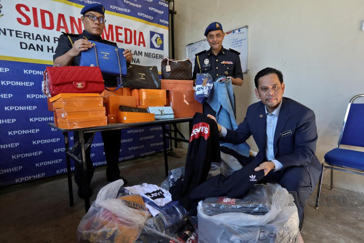 SAHARUDDIN Mohd Kia (kanan) memeriksa barangan tiruan yang berjaya dirampas. FOTO: Ghazali Kori