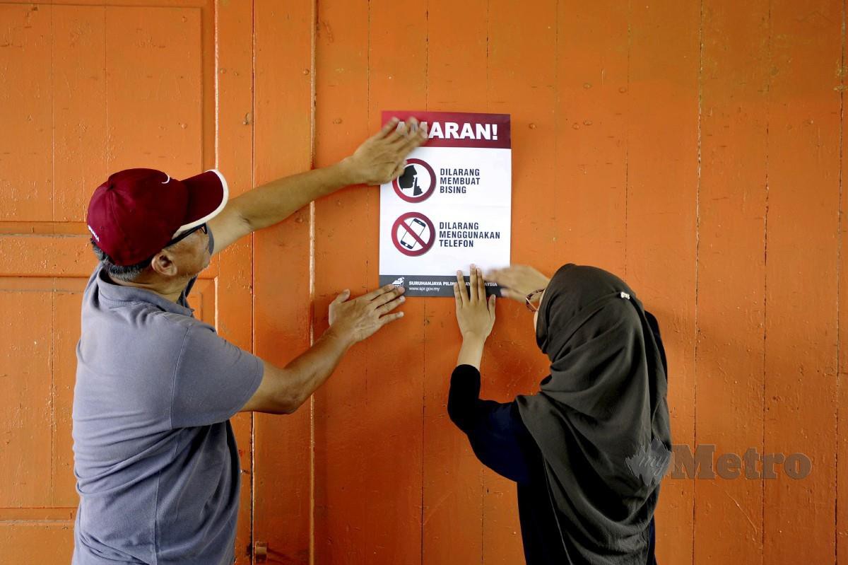 Petugas Suruhanjaya Pilihan Raya (SPR) menampal maklumat untuk perhatian pengundi di Sekolah Kebangsaan Syed Idrus, Ulu Kuang, Chemor, Perak. FOTO AIZUDDIN SAAD