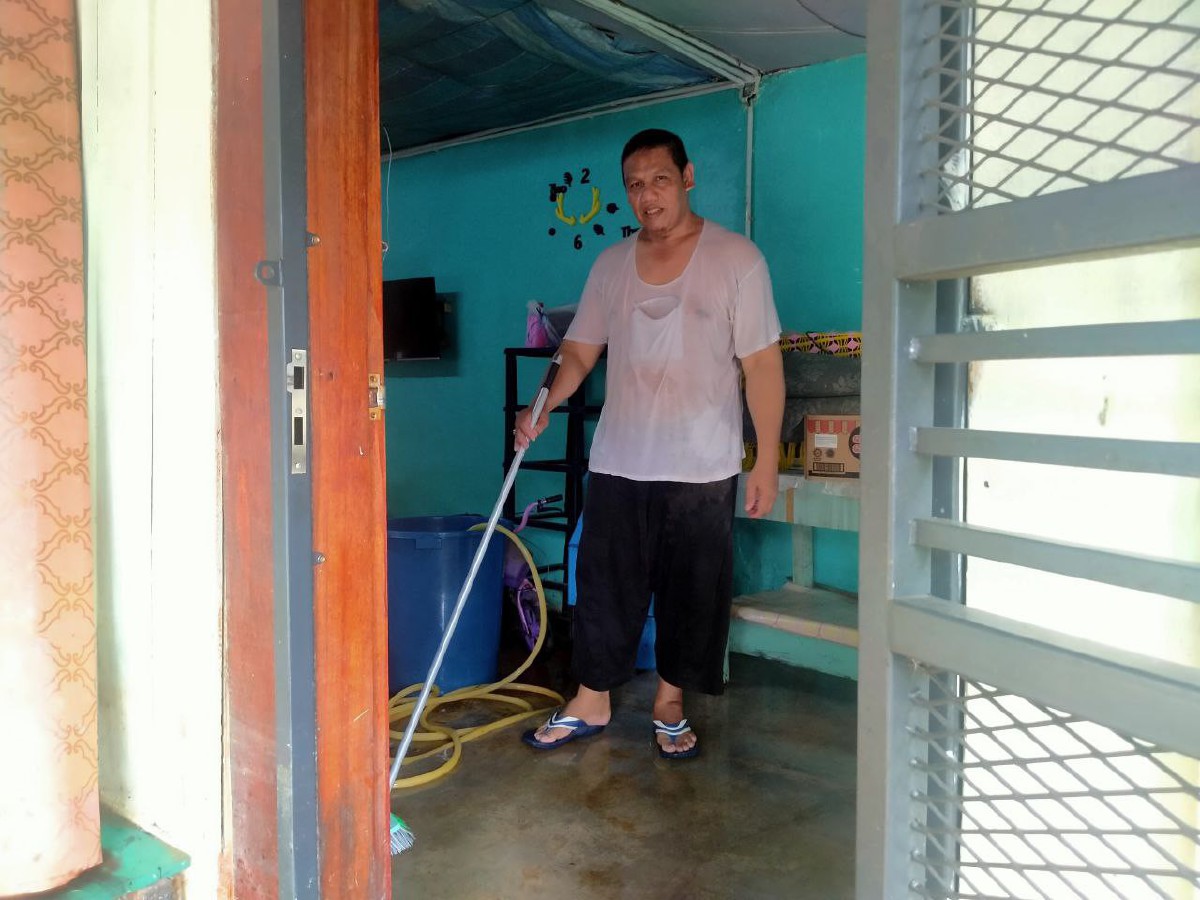 MOHAMAD Salehuddin mencuci rumah mentuanya setelah tiga minggu dilanda banjir. FOTO Muhamad Lokman Khairi.